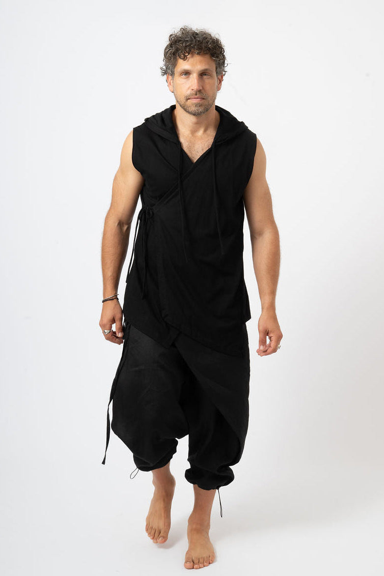 Man wearing a black sleeveless top and baggy pants on a white background