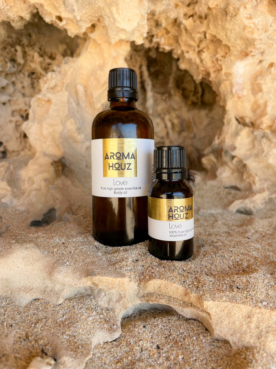 Two bottles of Aroma Houz essential oils against a sandy rock backdrop