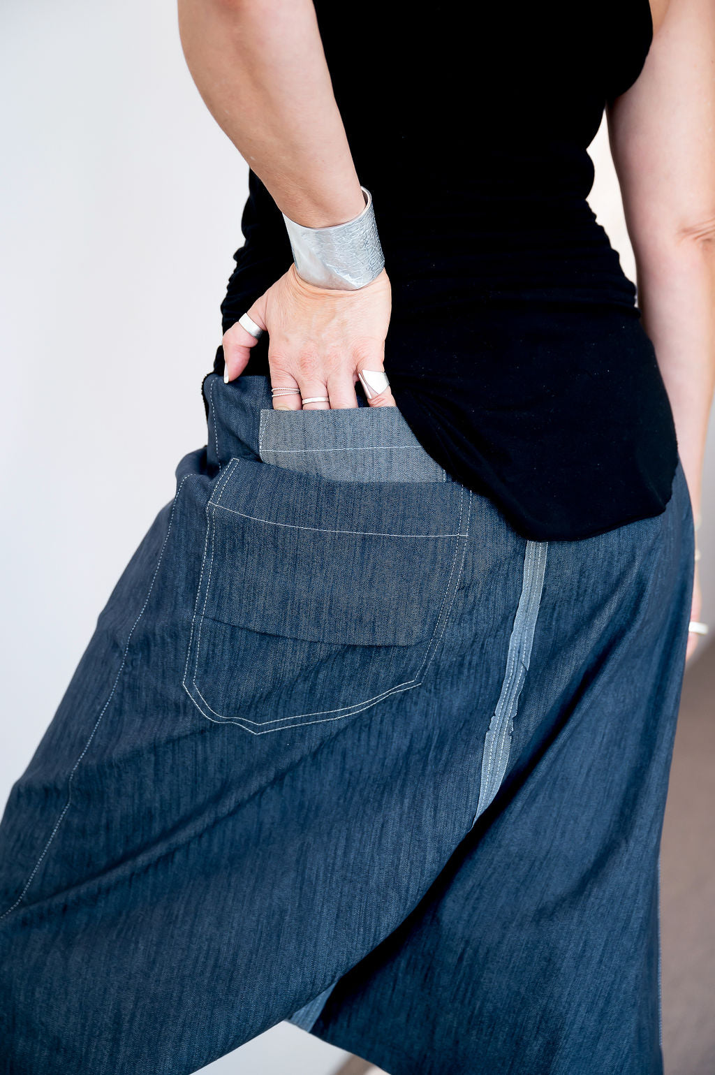 Close-up of a designer adjusting a textured denim garment, focusing on the unique pocket details and seams